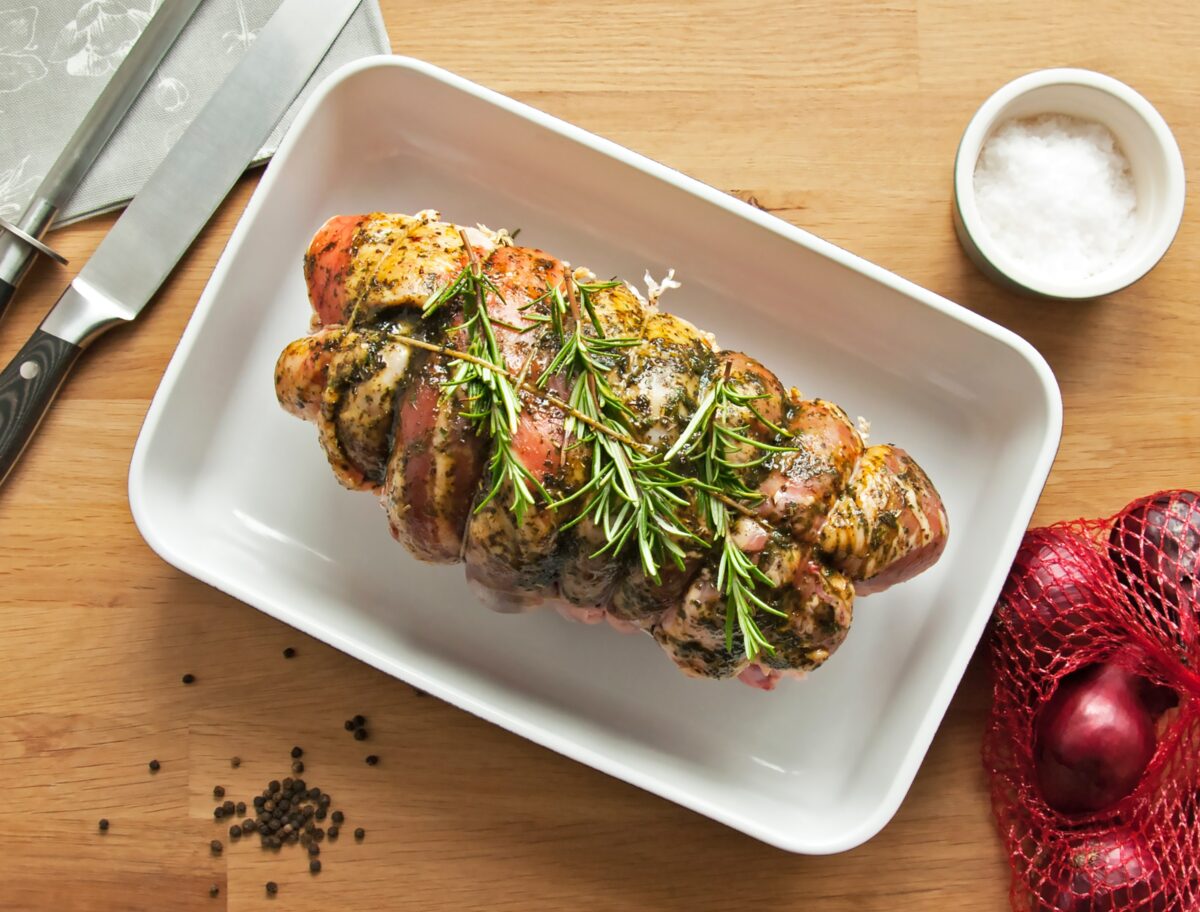 Photograph of a roasted leg of lamb with fresh rosemary
