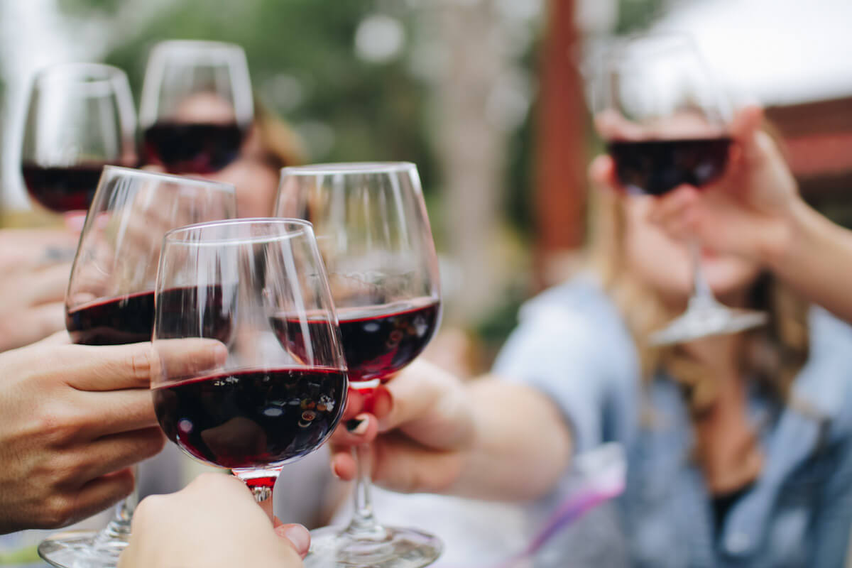 A group of people toasting with red wine. Photo by Kelsey Knight
