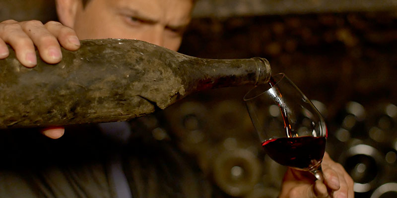 An old bottle of wine being poured in Somm Into The Bottle